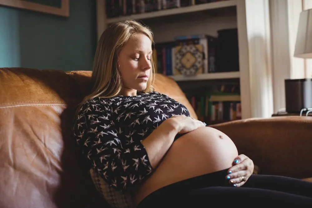 mulher grávida relaxando na sala de estar