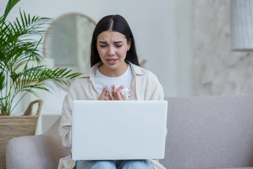 jovem mulher bonita sozinha em casa em depressão chorando morena sentada em casa e usando notebook