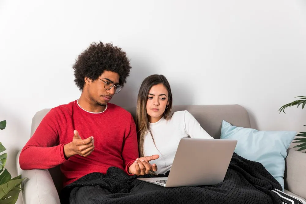 retrato de casal interracial usando laptop juntos