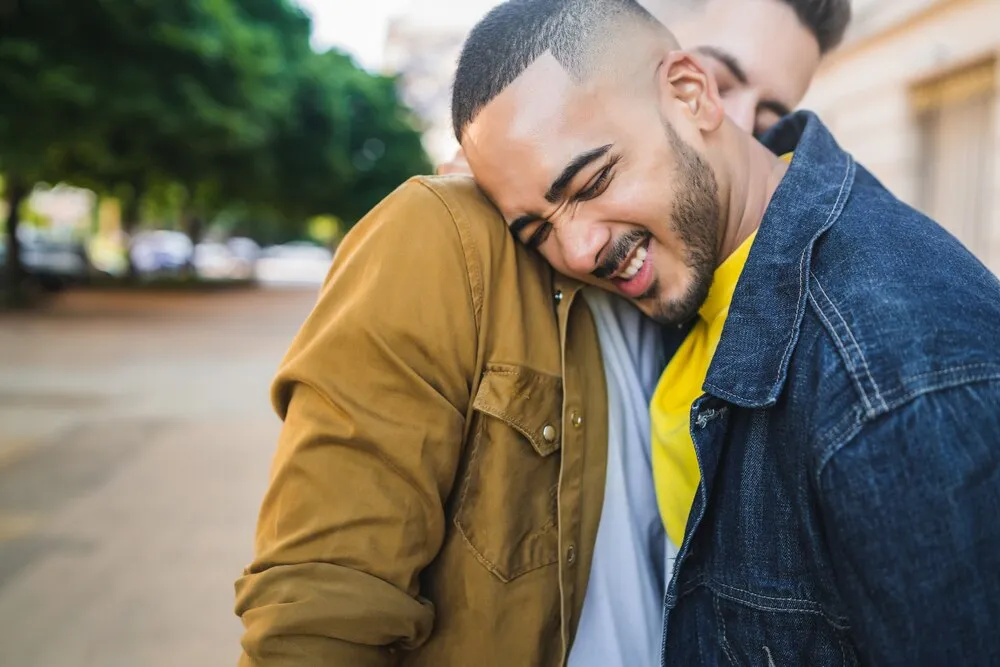 retrato de um casal gay feliz passando tempo juntos e se abraçando na rua. conceito de amor e lgbt.