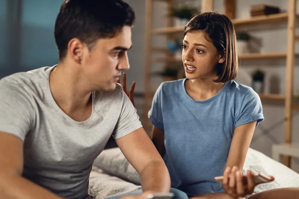 Jovem casal tendo um conflito e discutindo no quarto, o foco está na mulher.
