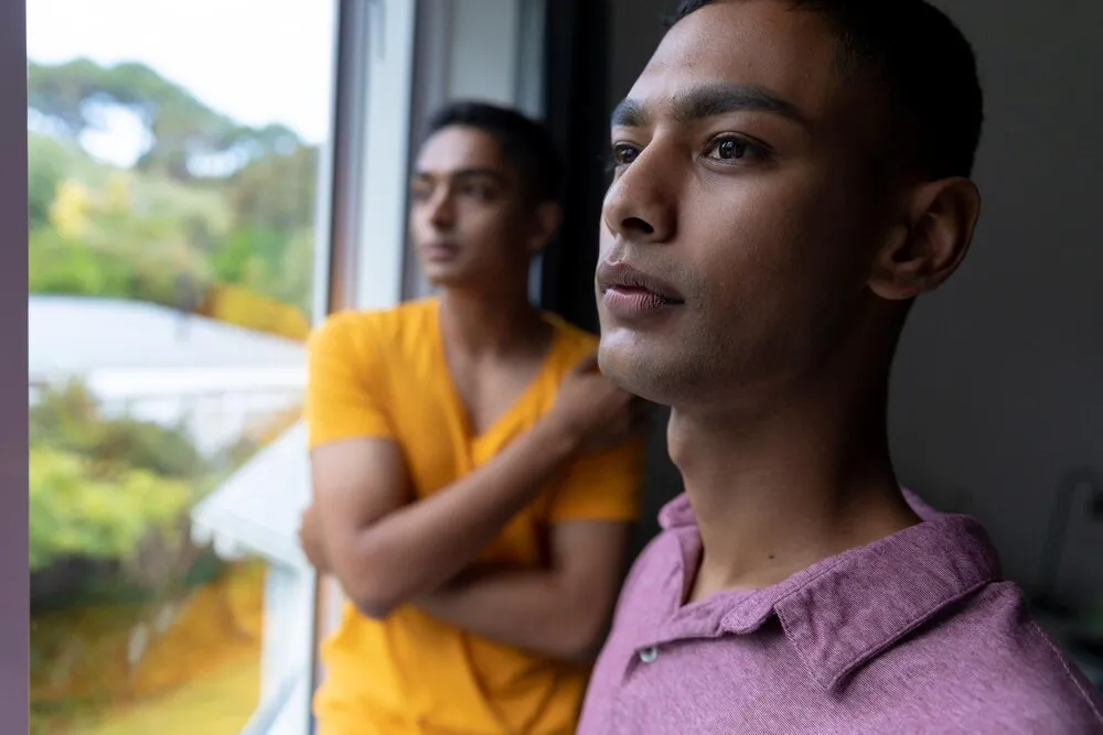 casal gay diverso olhando pela janela e pensando