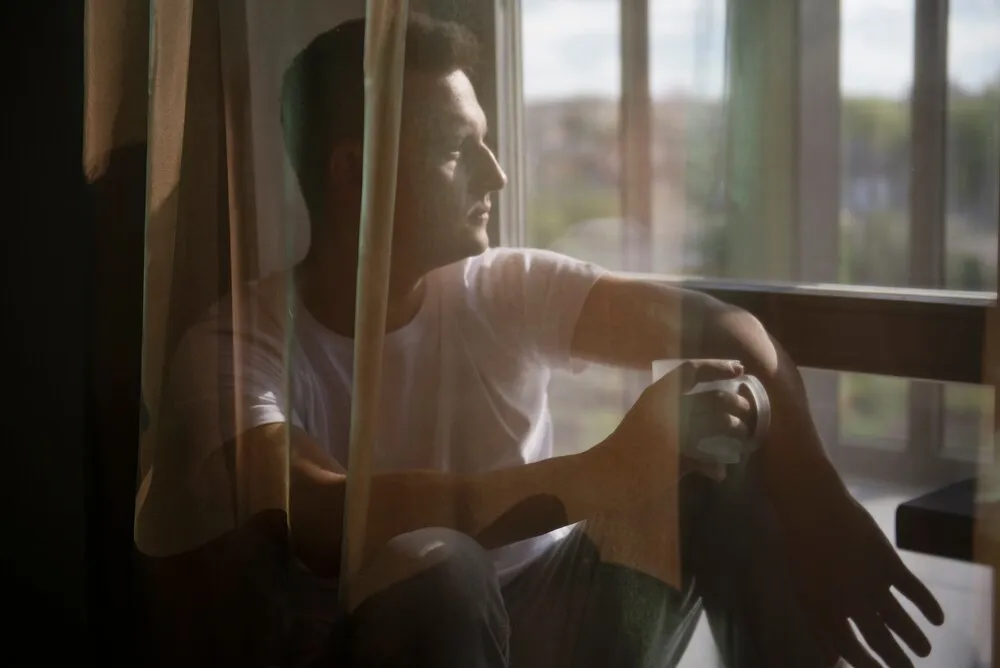 retrato criativo de um homem com cortinas e sombras da janela