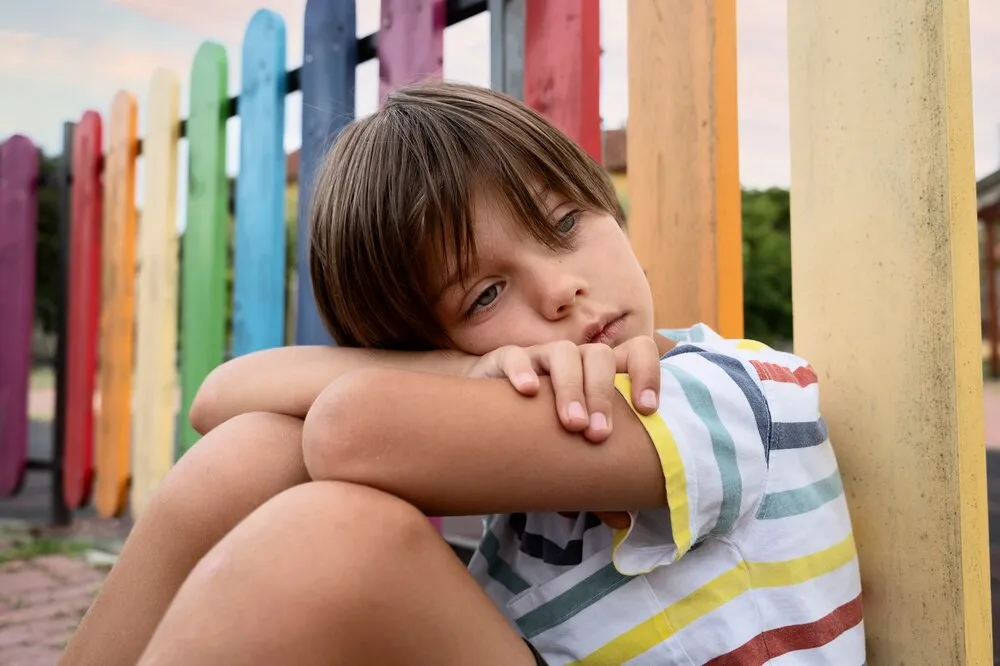 plano médio menino triste no parque